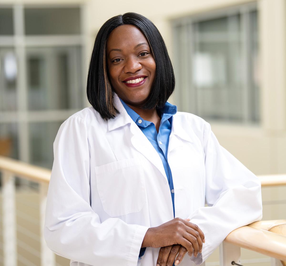 A nursing student in their coat posing for a photo.